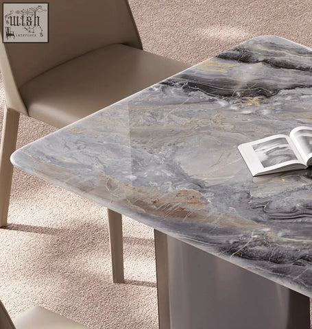 A sleek angela marble dining table with a polished gray marble top featuring black and gold veining for luxury dining