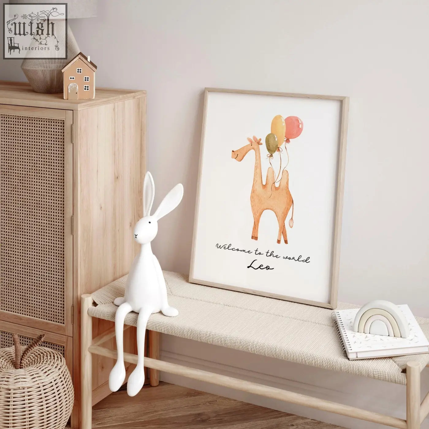 Framed watercolor animal prints of a tan camel holding colorful balloons with welcome to the world leo text for nursery decor