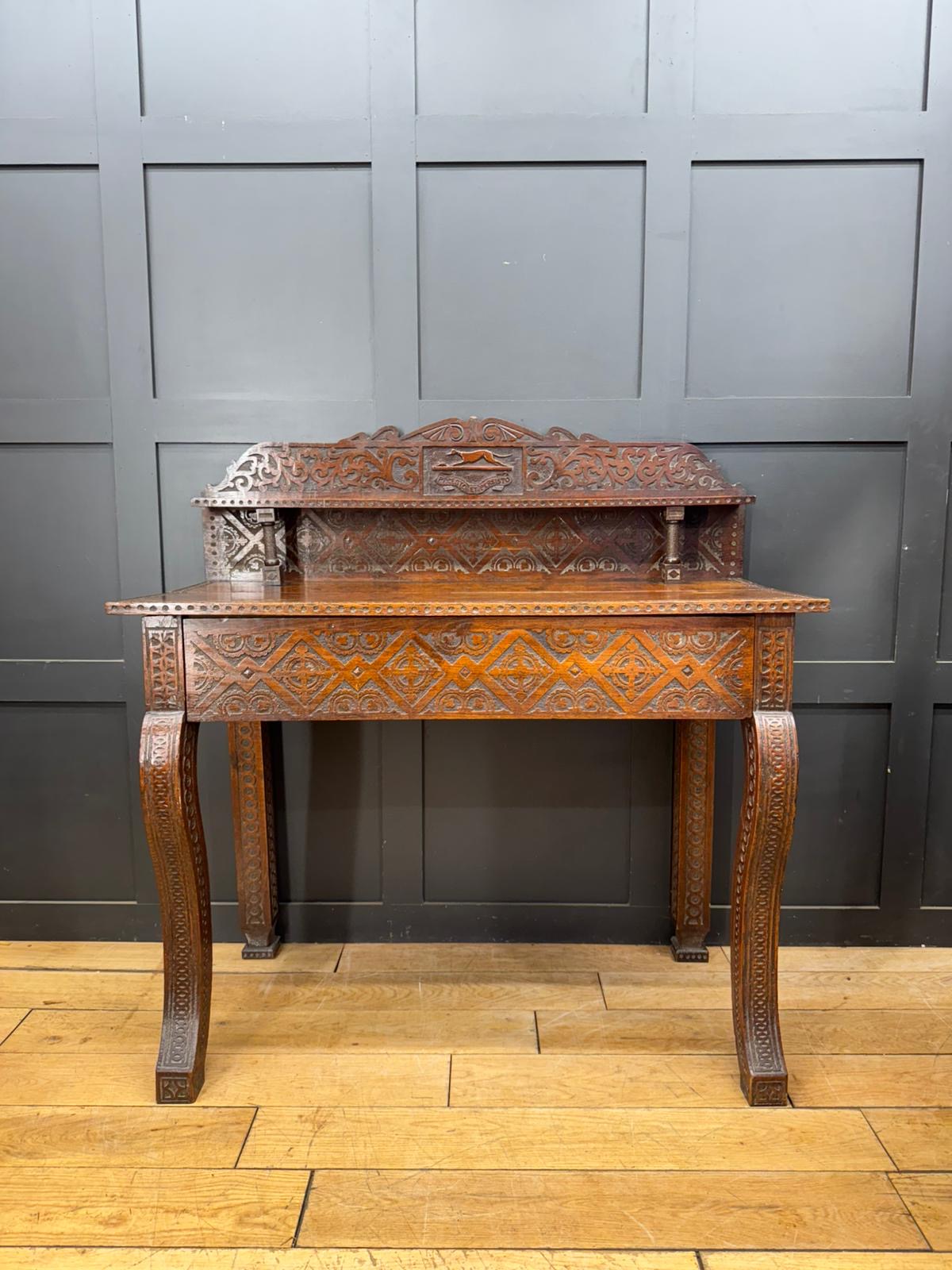 Antique carved oak hall table with intricate inlaid patterns and ornate scrollwork on legs and crest