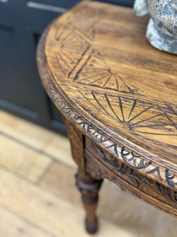 Antique carved oak console table with intricate fan and leaf patterns along its curved wooden edge