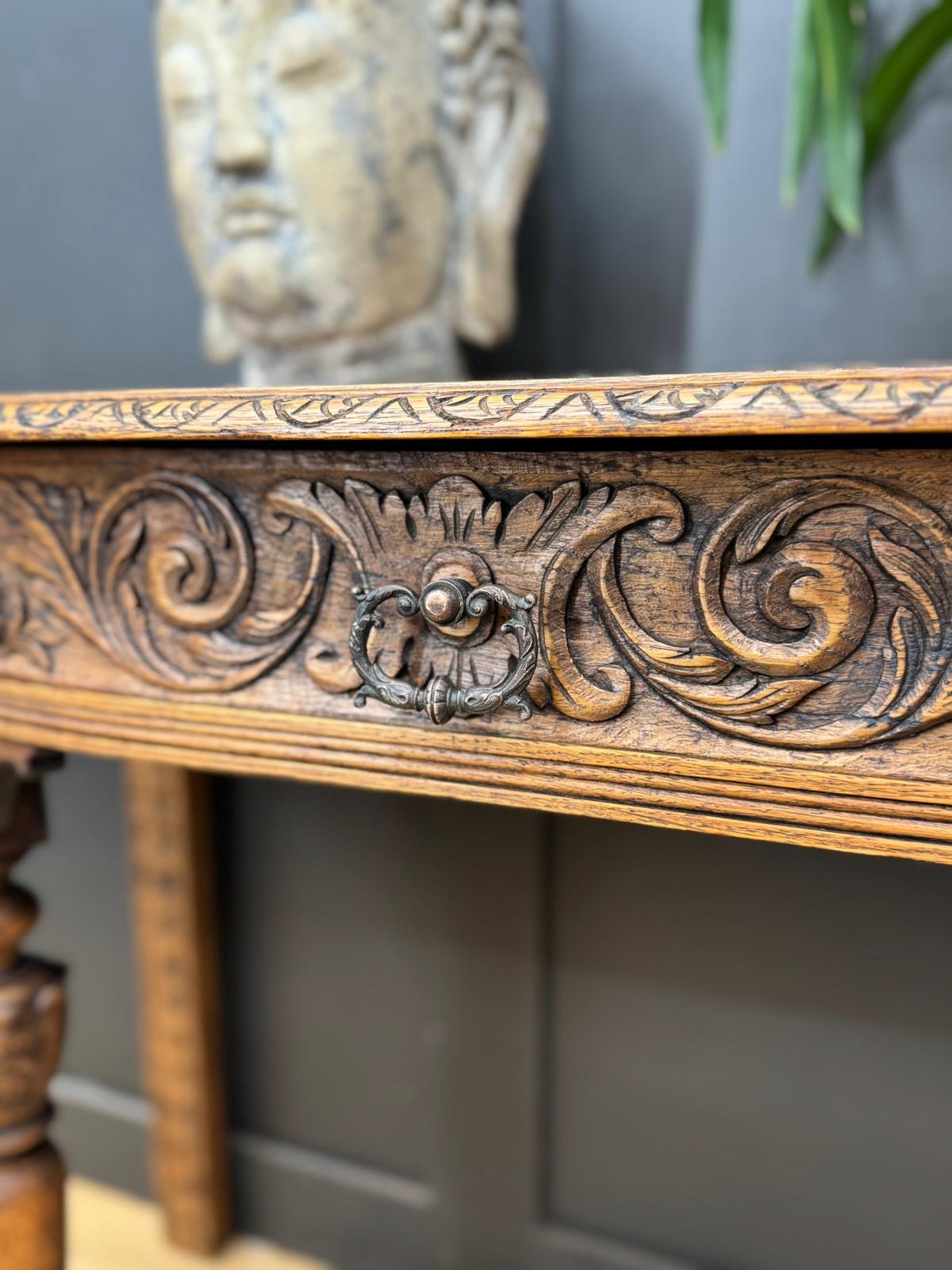 Antique carved oak console table with dark bronze drawer pull and intricate floral carvings for hallway or desk use