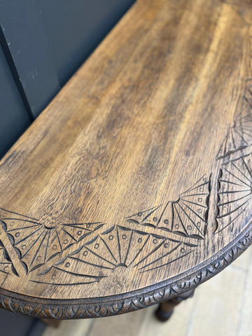 Antique carved oak console table with intricate fan-shaped wooden carvings along the edge for hallway use