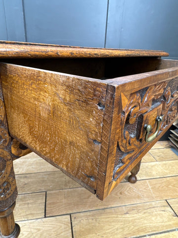 Antique carved oak side table with drawer featuring intricate floral scrollwork brass hardware and warm golden-brown finish