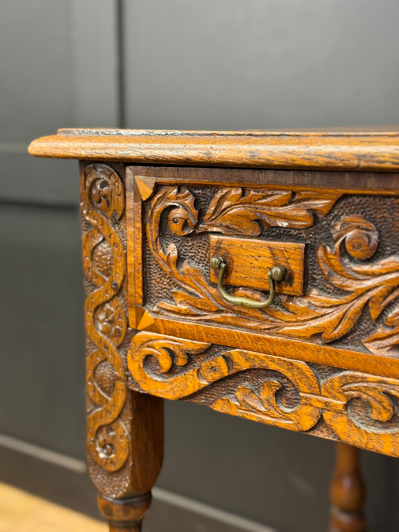 Antique carved oak side table with intricate floral carvings and brass handle perfect as a hall table or lamp table