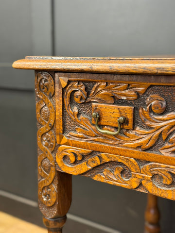 Antique carved oak side table with intricate floral carvings and brass handle perfect as a hall table or lamp table