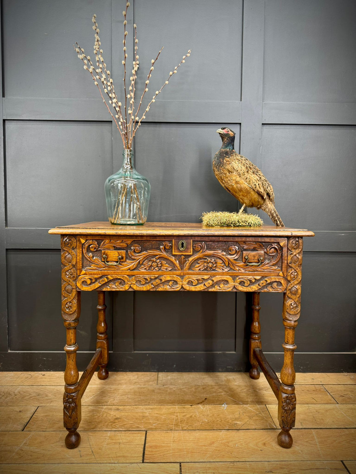 Antique carved oak hall table with ornate floral scrollwork front panel, central keyhole, and two drawers