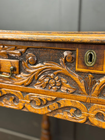 Antique carved oak side table with drawer featuring intricate floral carvings and brass hardware as a hall table