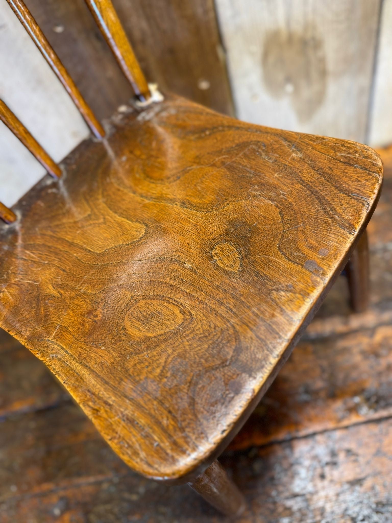 Antique childs chair with elm seat in warm brown wood finish with visible wood grain patterns for nursery display