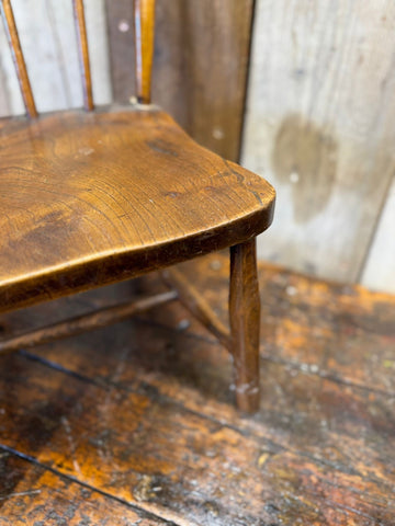 Antique childs chair with elm seat finished in warm honey tone and visible grain patterns for nursery or display use