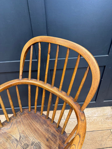 A warm medium-toned antique elm windsor armchair with curved back and spindles perfect for farmhouse decor