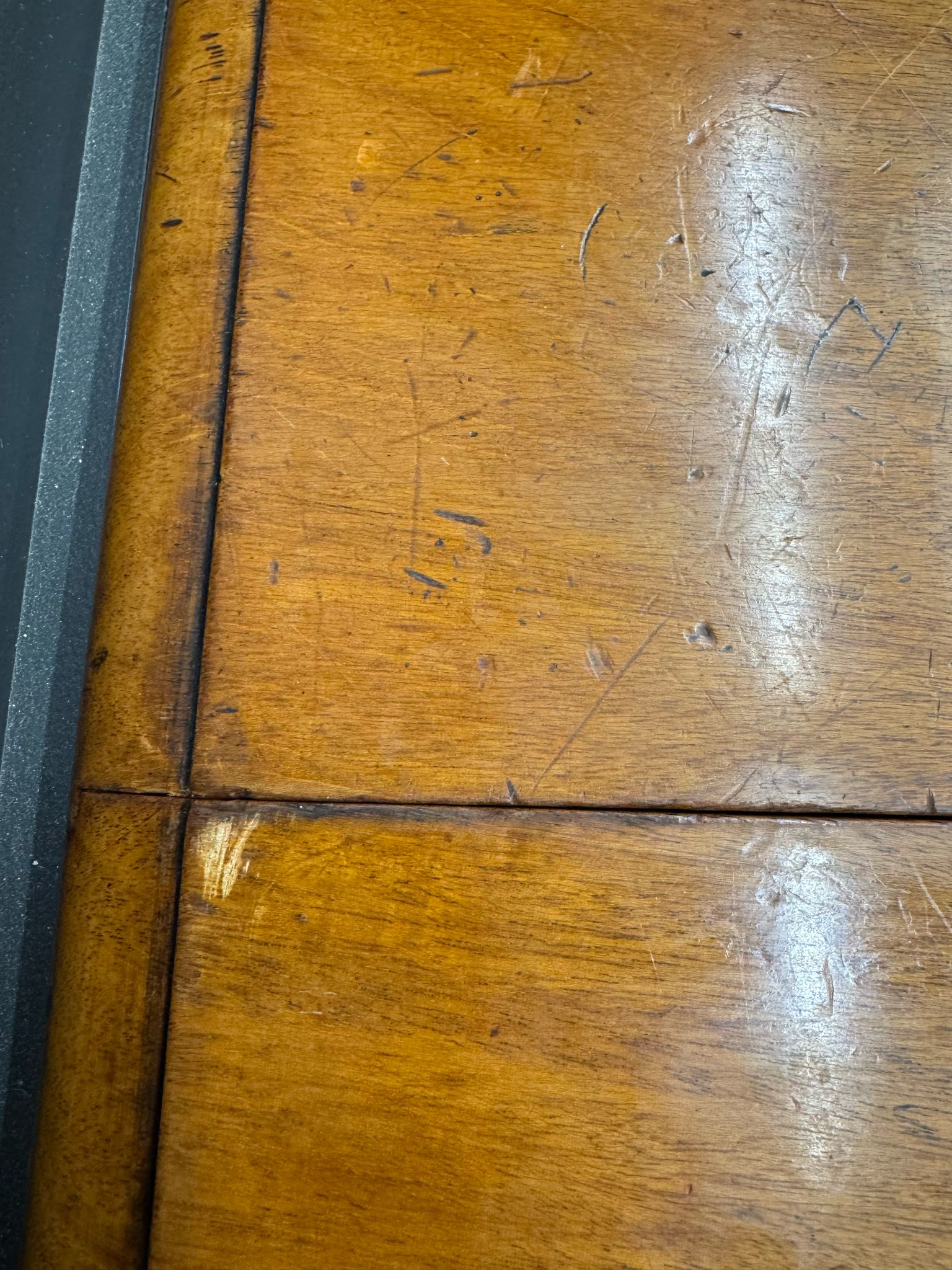 Worn wooden surface of antique mahogany drop leaf pembroke table with drawer showing grain and warm amber finish