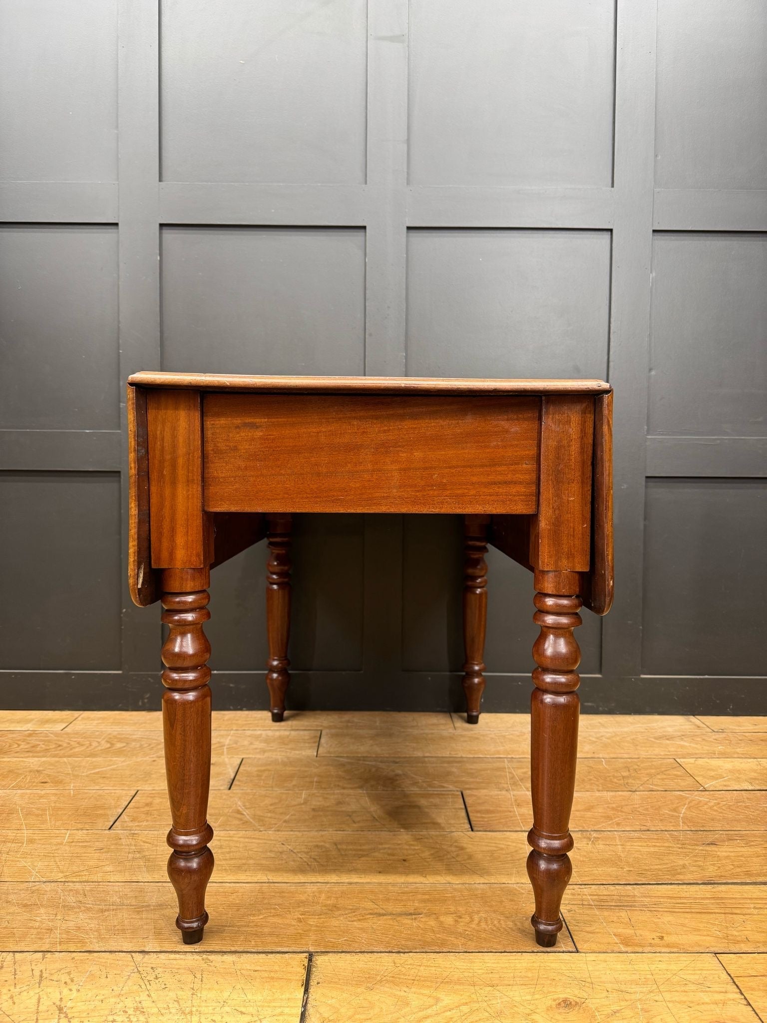 Antique extending mahogany pembroke table with drop leaf, turned legs, warm polished finish, and a drawer storage