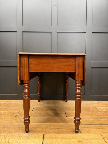 Antique extending mahogany pembroke table with drop leaf, turned legs, warm polished finish, and a drawer storage