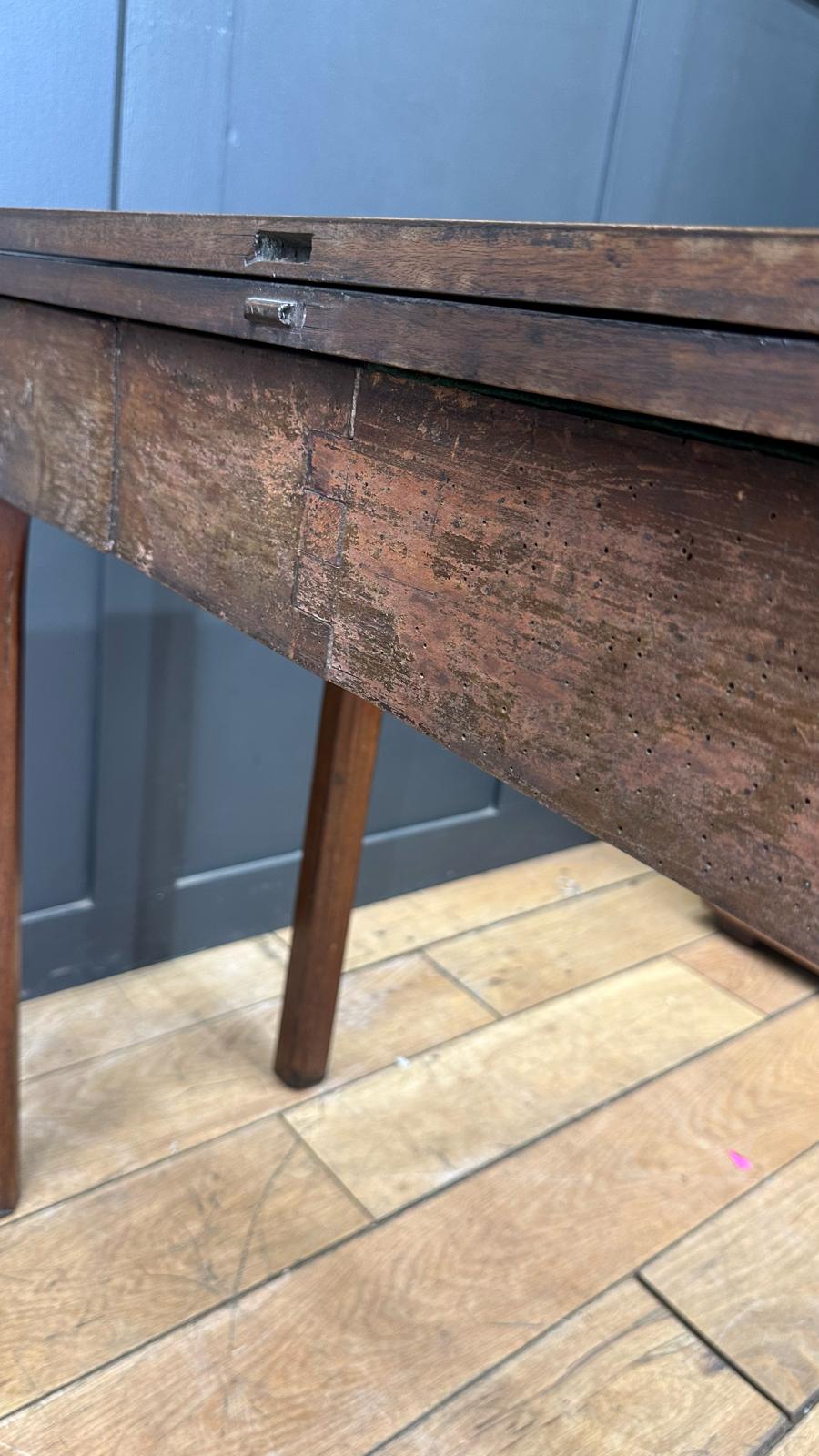 Antique dark wood folding mahogany tea table with visible grain and metal hinge mechanism for games or occasional use