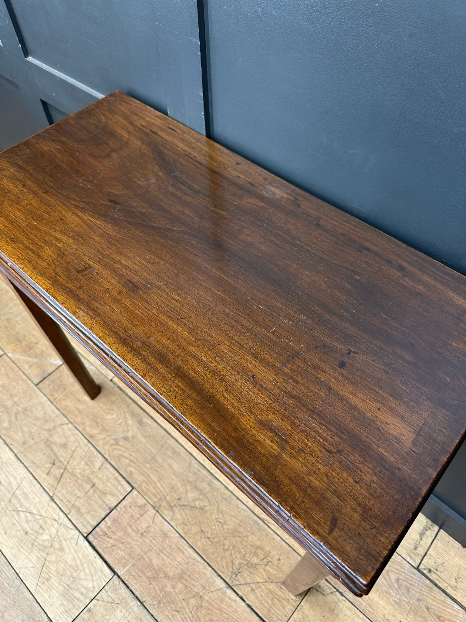 A polished dark brown mahogany tea table with smooth reflective surface and visible wood grain perfect for games or occasions