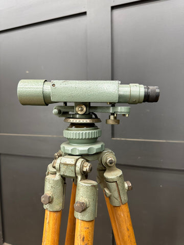 Vintage green metal hall brothers theodolite surveying instrument mounted on wooden tripod for industrial use