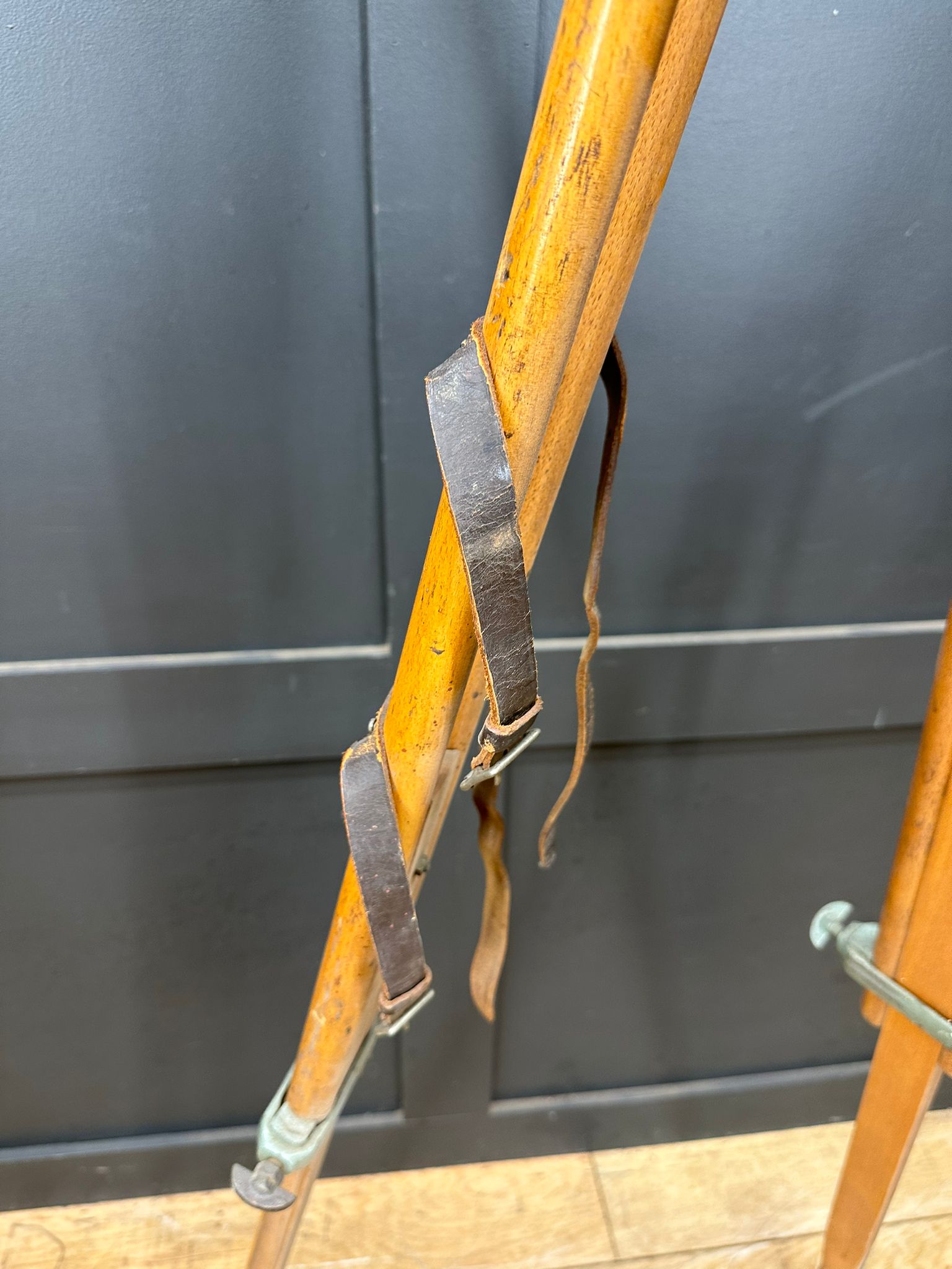 Vintage wooden ski poles with worn leather straps and metal fittings linked to hall brothers antique surveying gear