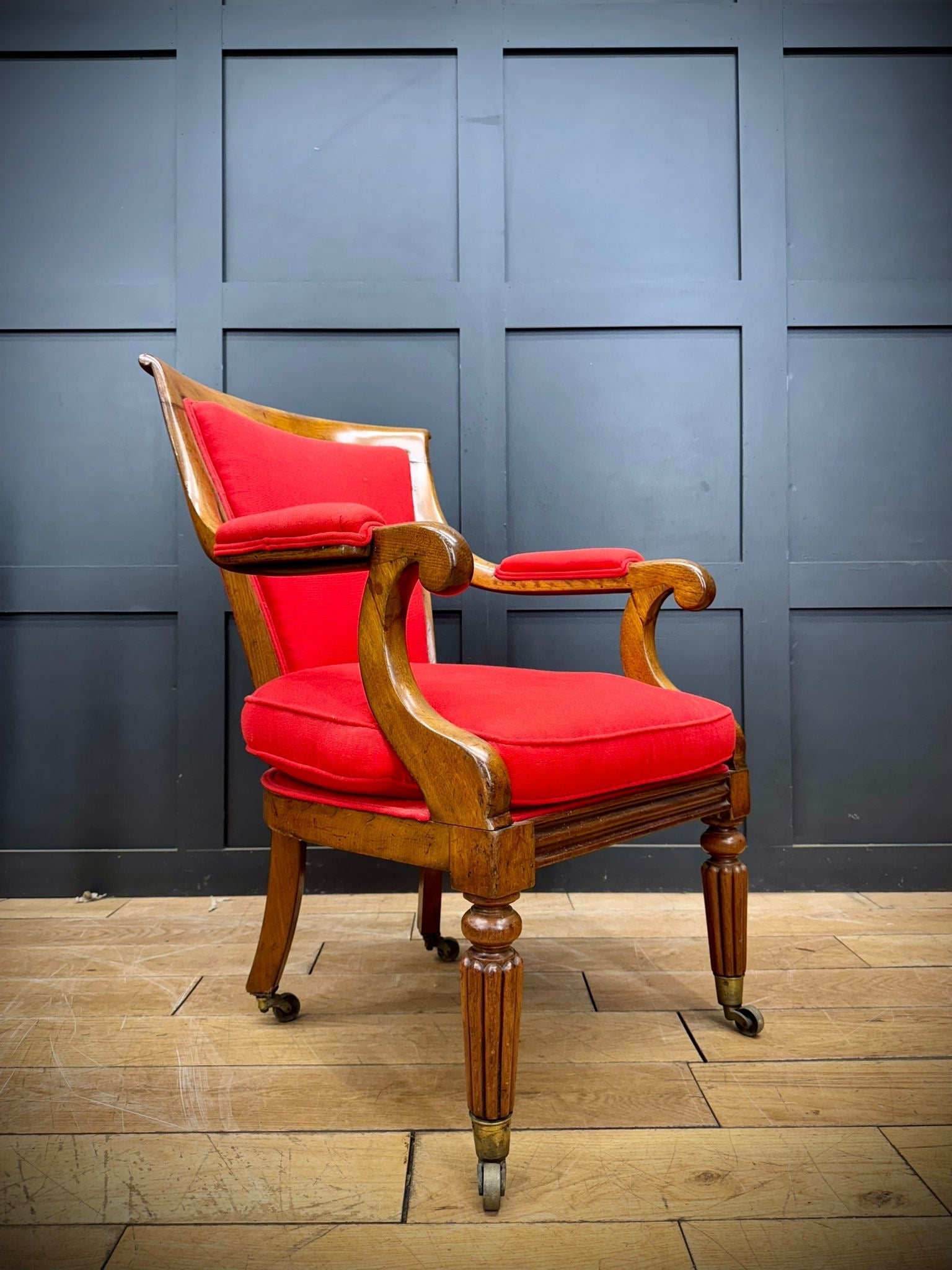 Antique mahogany armchair with red upholstered seat and back featuring ornate carvings and turned legs