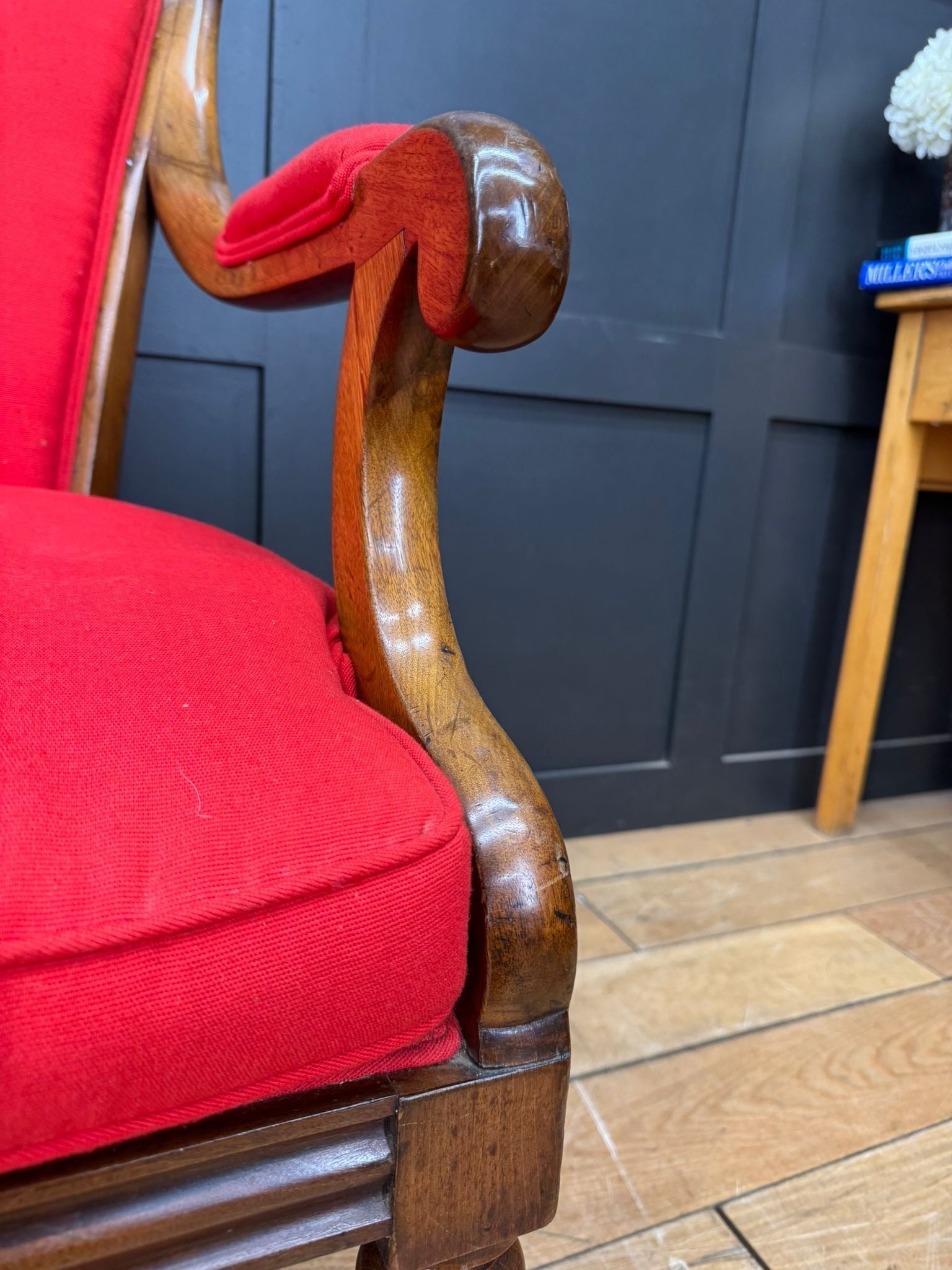 Antique mahogany armchair with red upholstery and polished curved wooden frame in victorian empire style