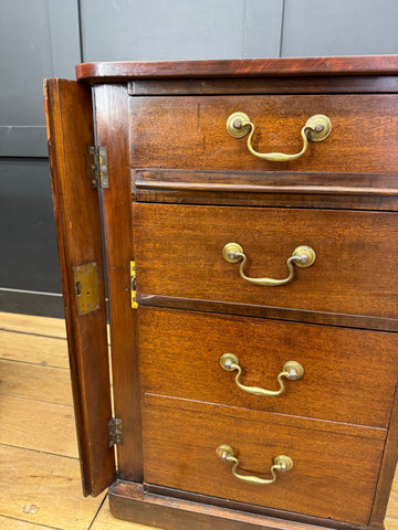 Antique mahogany twin pedestal desk with mahogany chest of drawers featuring brass handles and hinged side panel