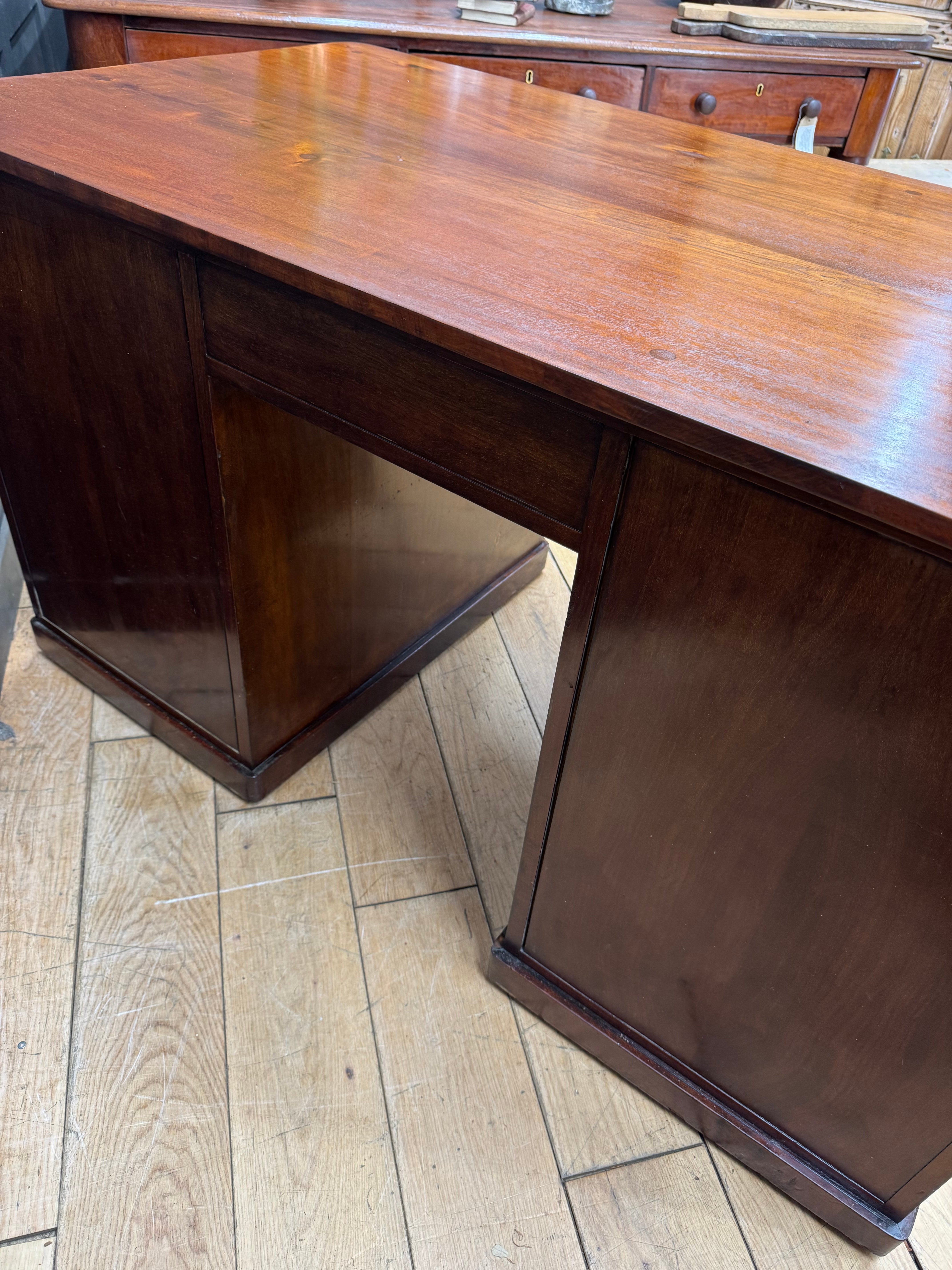 A polished antique mahogany twin pedestal desk with dark brown wood and smooth reflective surface for office use