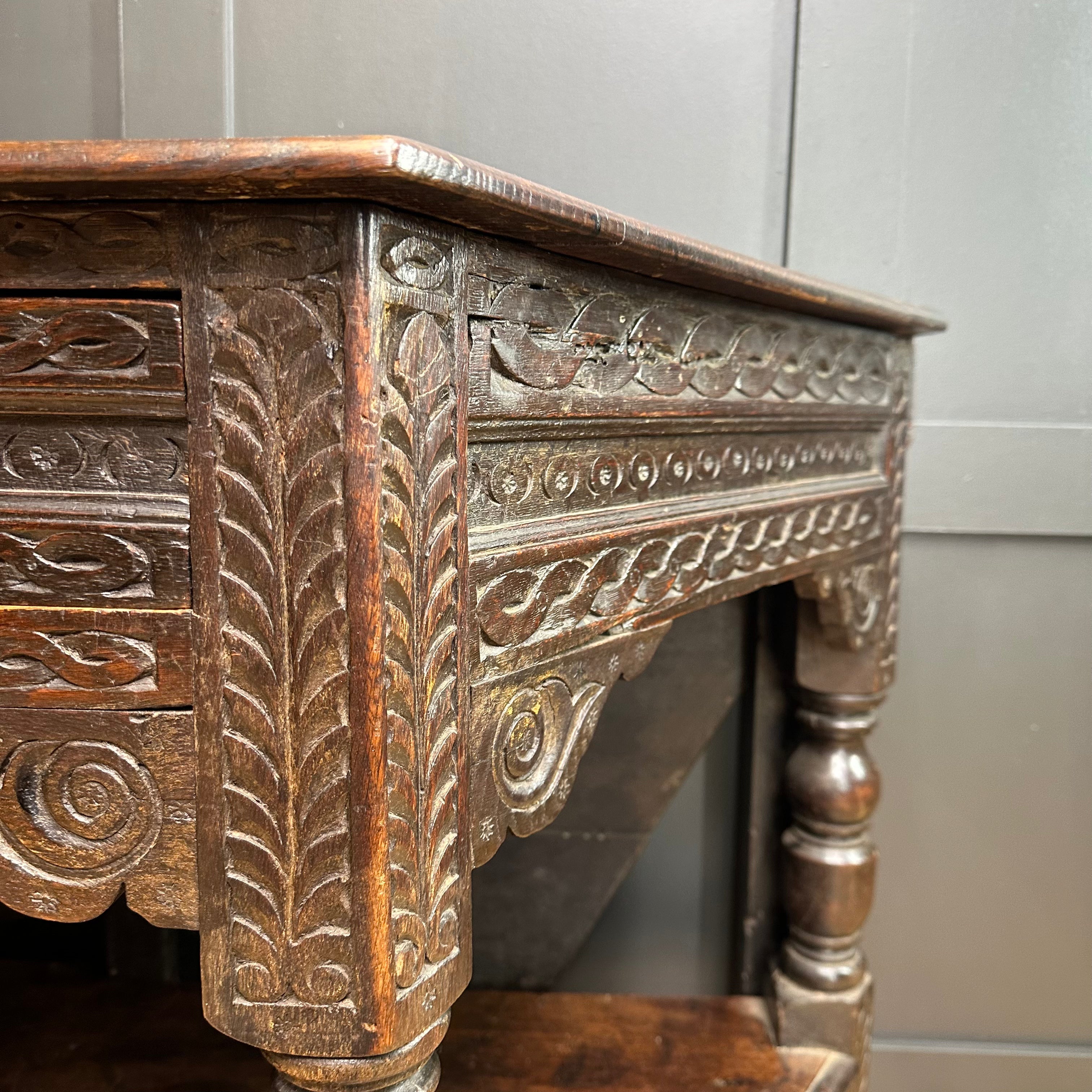 Antique oak credence table with dark wood and intricate carved leaf and scrollwork detailing as sideboard or lamp table