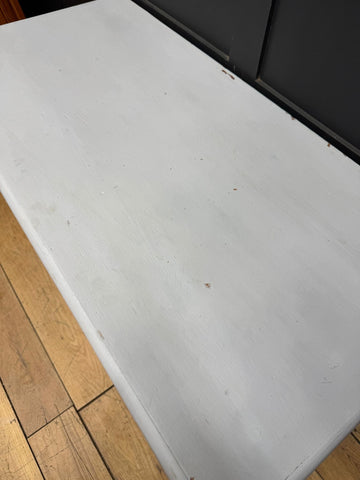 White painted wooden table surface next to antique painted blanket chest for shoe storage and tv stand use