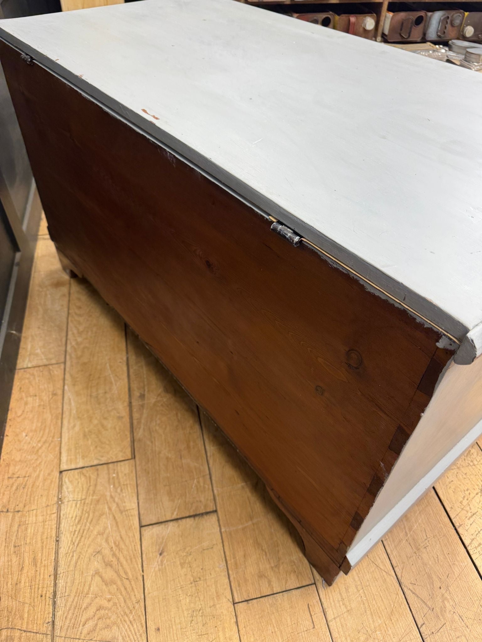 Vintage wooden blanket chest with white painted top and dark wood sides featuring metal hinges for shoe storage