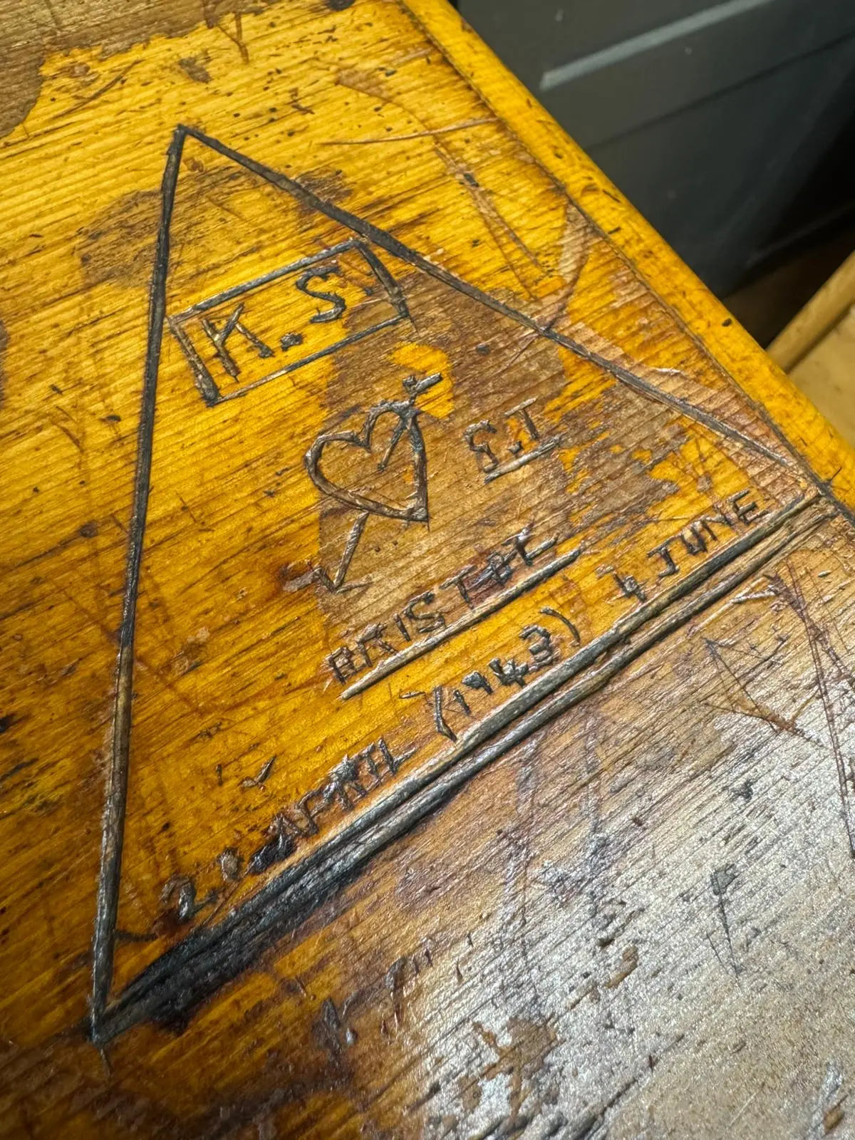 A weathered yellow pine chest back with a carved triangular emblem featuring initials heart and date for country house storage