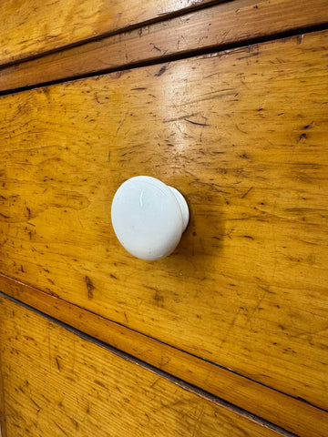 White ceramic drawer knob with smooth rounded design on antique pine chest for country house storage