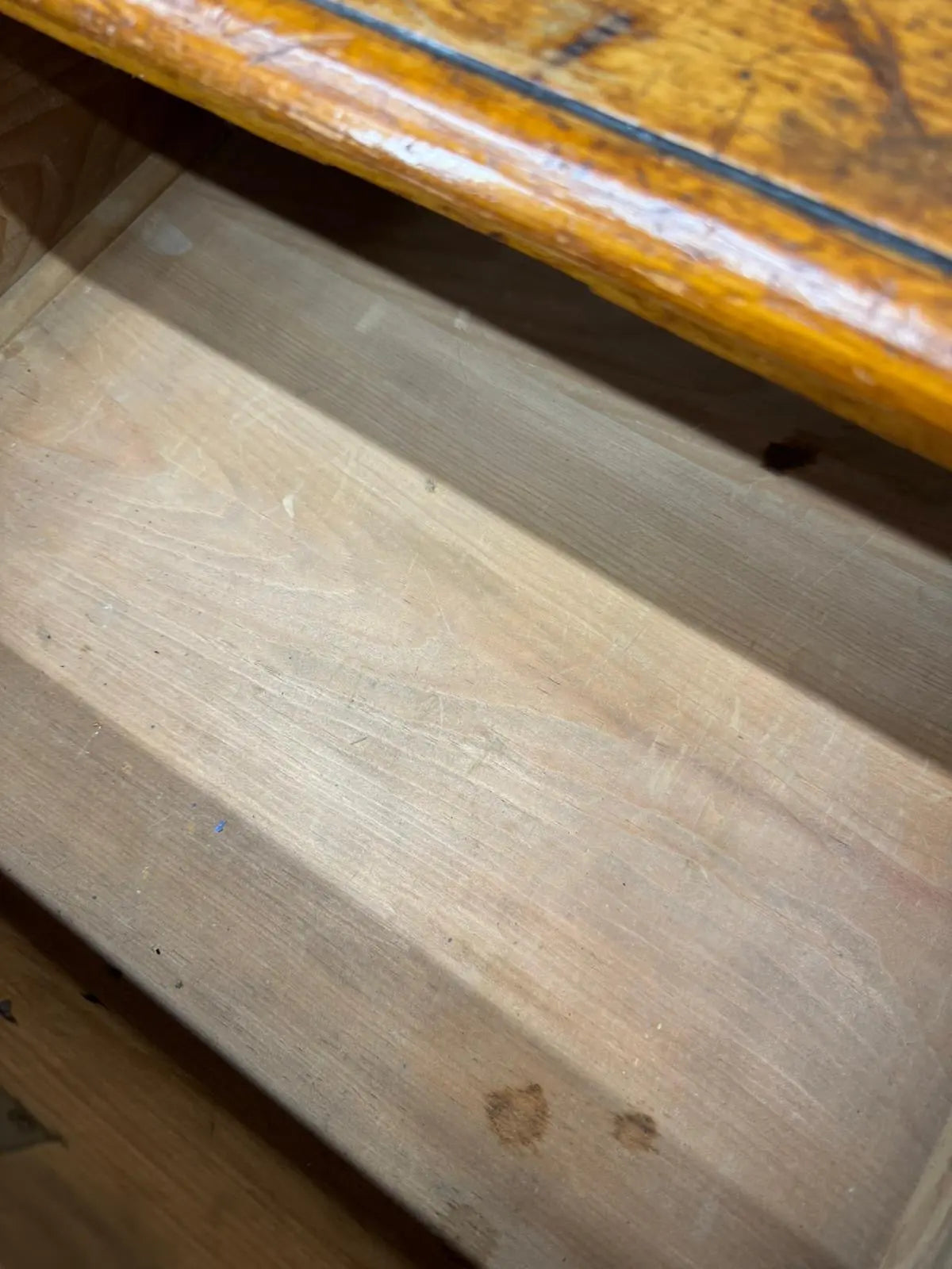 A worn pine chest drawer with light natural wood finish and visible grain from an antique country house storage