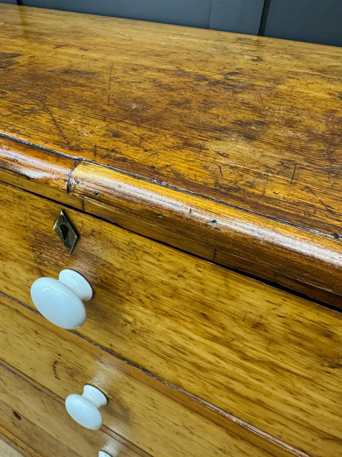 Antique yellow pine chest of drawers with white ceramic knobs and brass keyhole perfect for country house storage