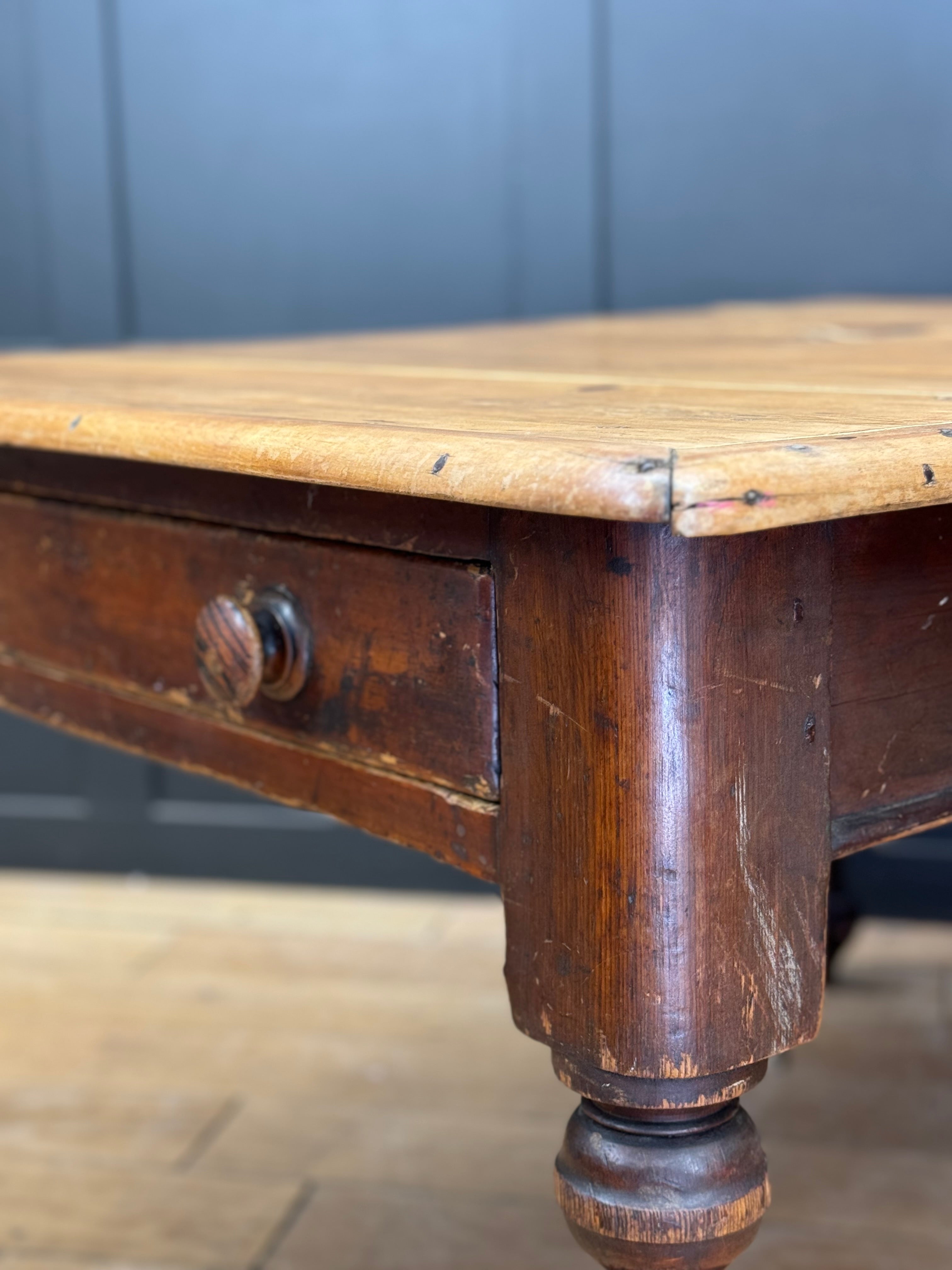 Antique pine kitchen table with worn light wood top and dark stained legs featuring turned feet vintage farmhouse style