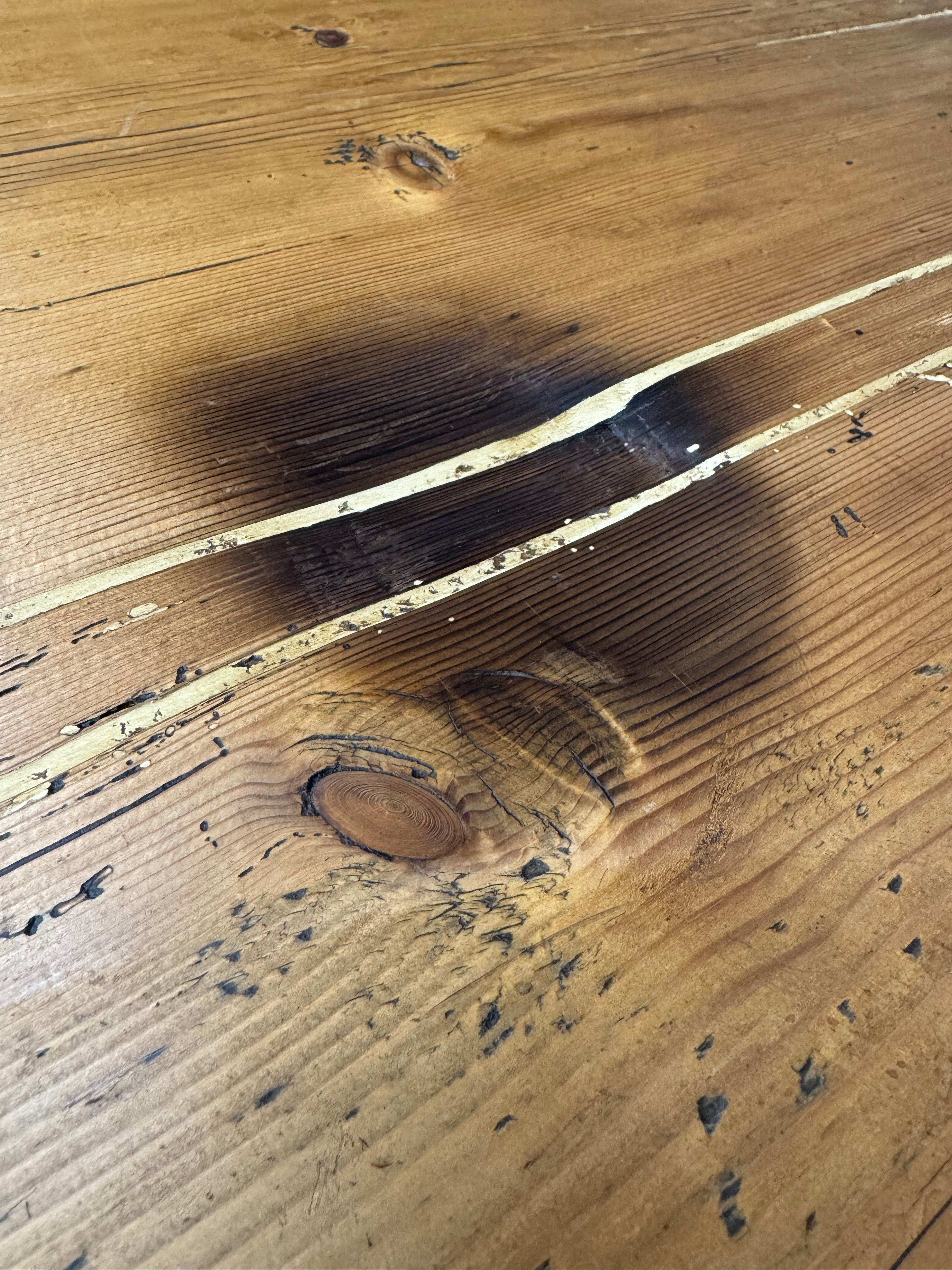Rustic farmhouse pine kitchen table with darkened cracks and visible knots on antique wooden surface
