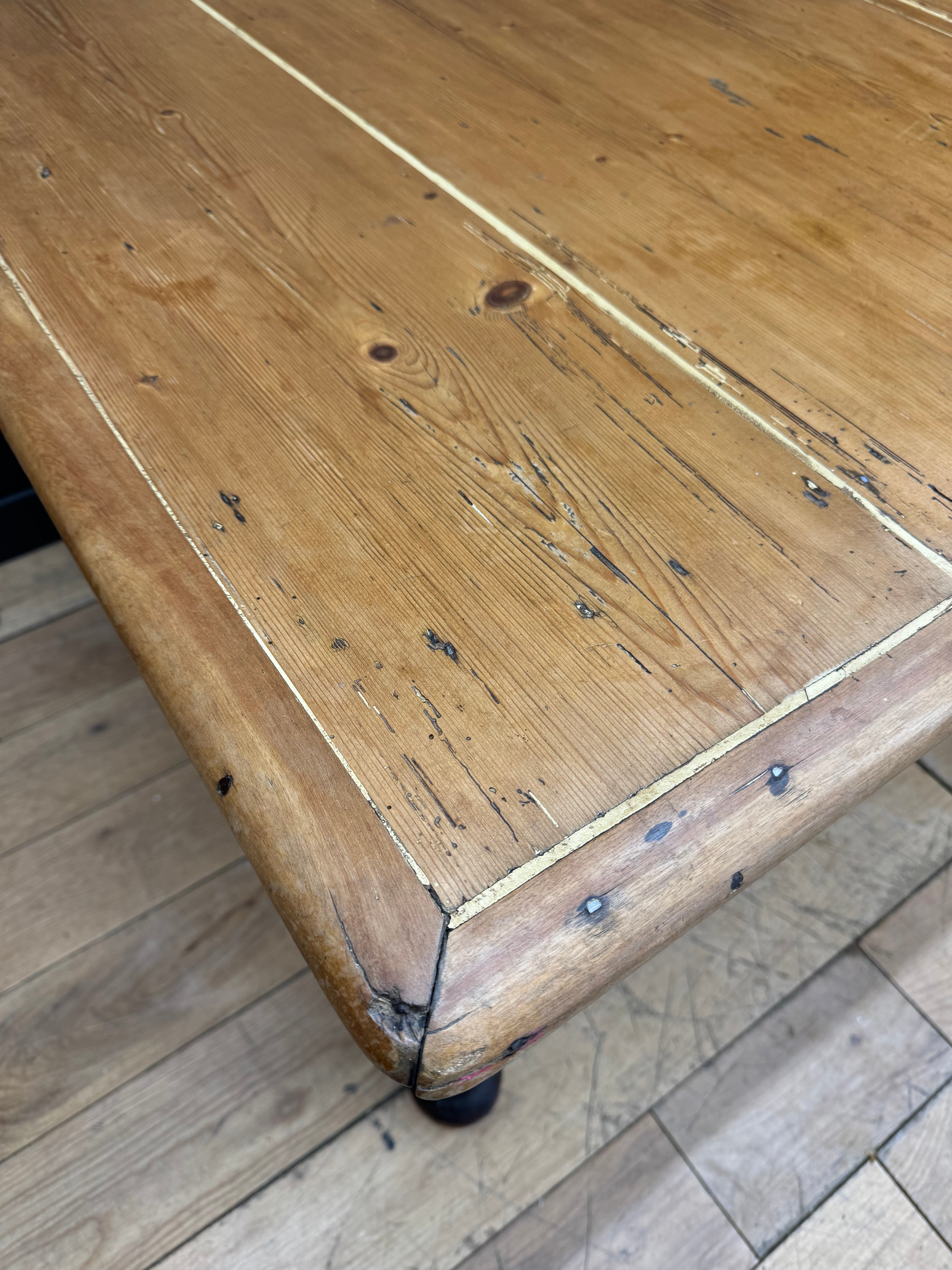 Rustic light brown antique pine kitchen table with visible grain and slightly worn farmhouse finish
