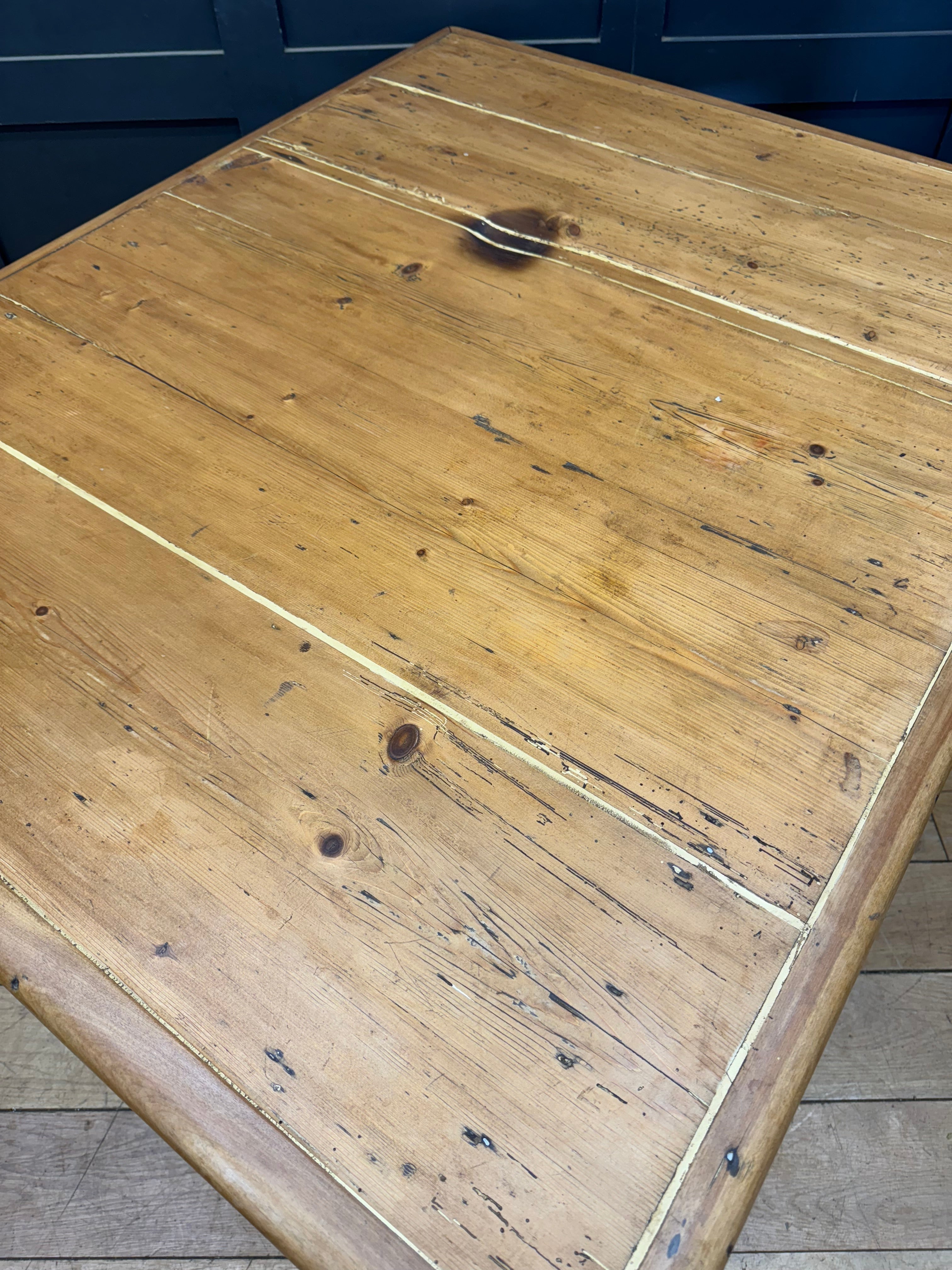 A rustic light brown pine kitchen table with visible grain and knots perfect for farmhouse or victorian style rooms
