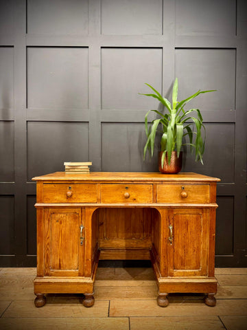 Antique pine pedestal desk with three drawers two cupboard doors brass handles and turned wooden legs in oak finish