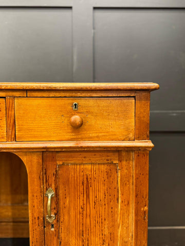 Antique pine pedestal desk dressing table with warm amber finish, single drawer, door, and brass hardware