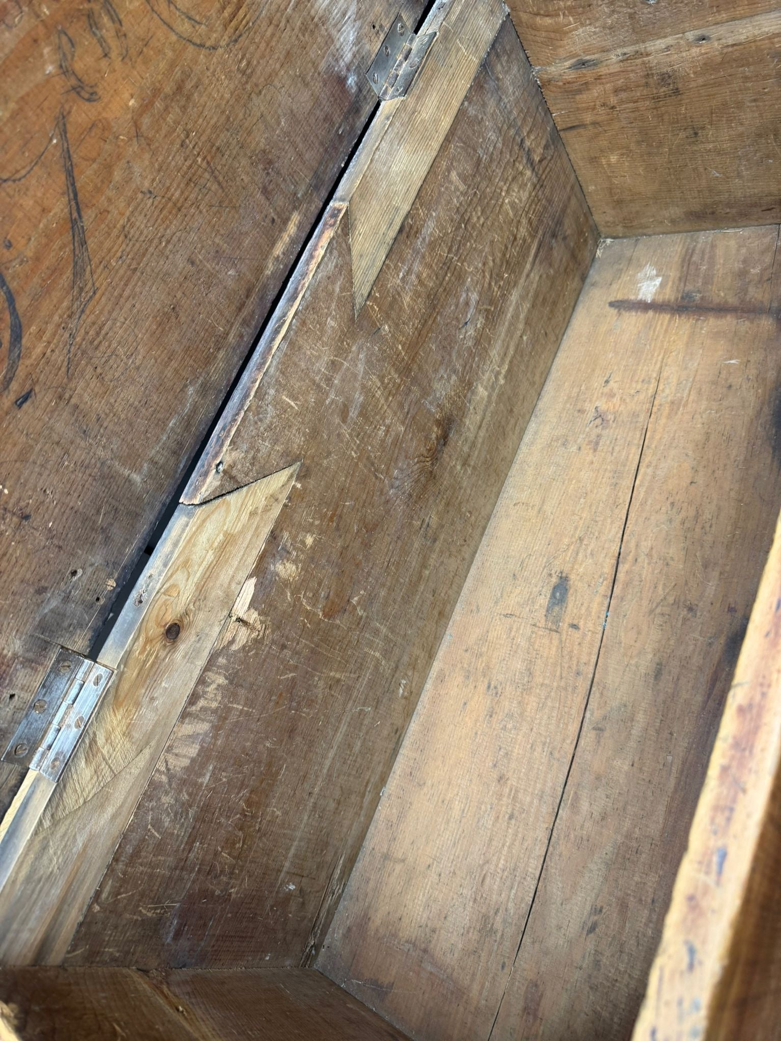 Worn antique pine storage chest with chipped paint, visible wood grain, and metal hinges for rustic blanket storage