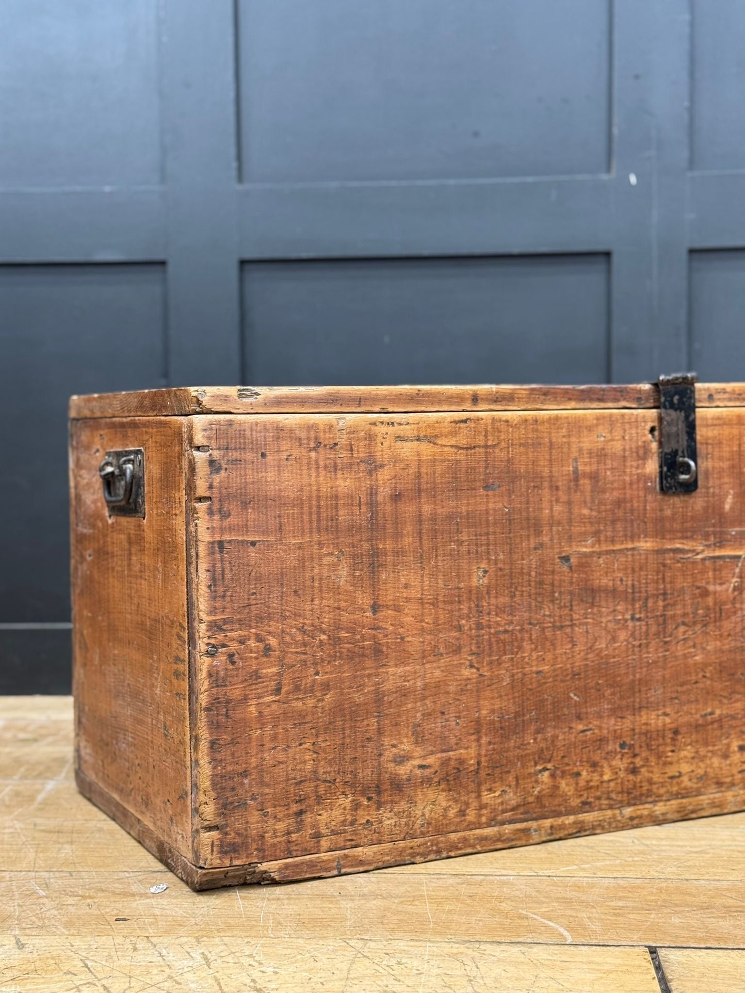 Antique pine storage chest with weathered wood and dark metal latches used as a rustic blanket box or coffee table trunk
