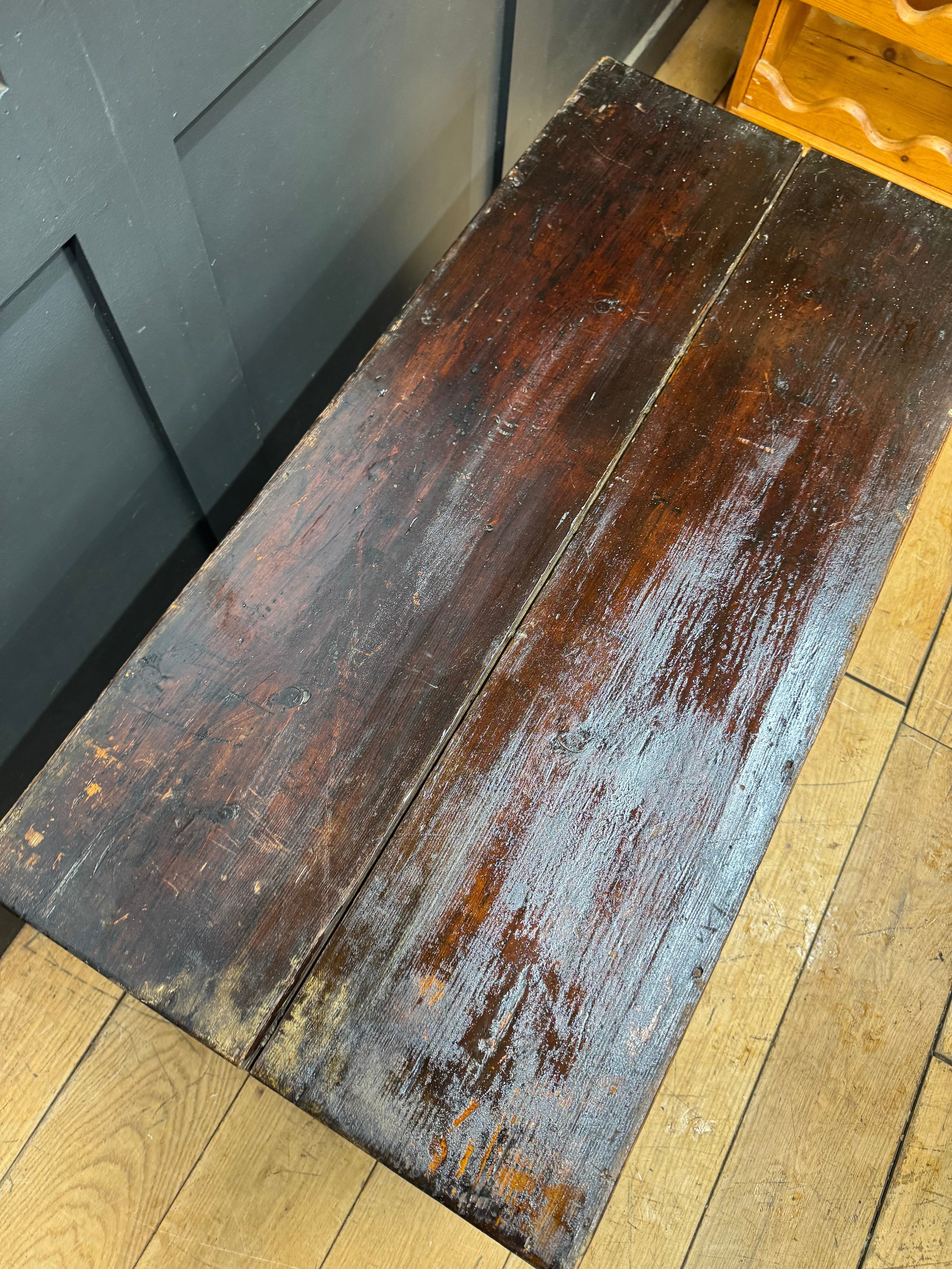 A weathered dark brown wooden bench with rustic aged finish used as a coffee table and storage chest