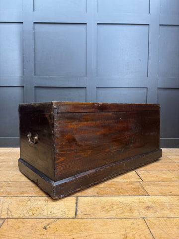 Dark brown antique pine trunk chest with metal handle used as coffee table and rustic storage box