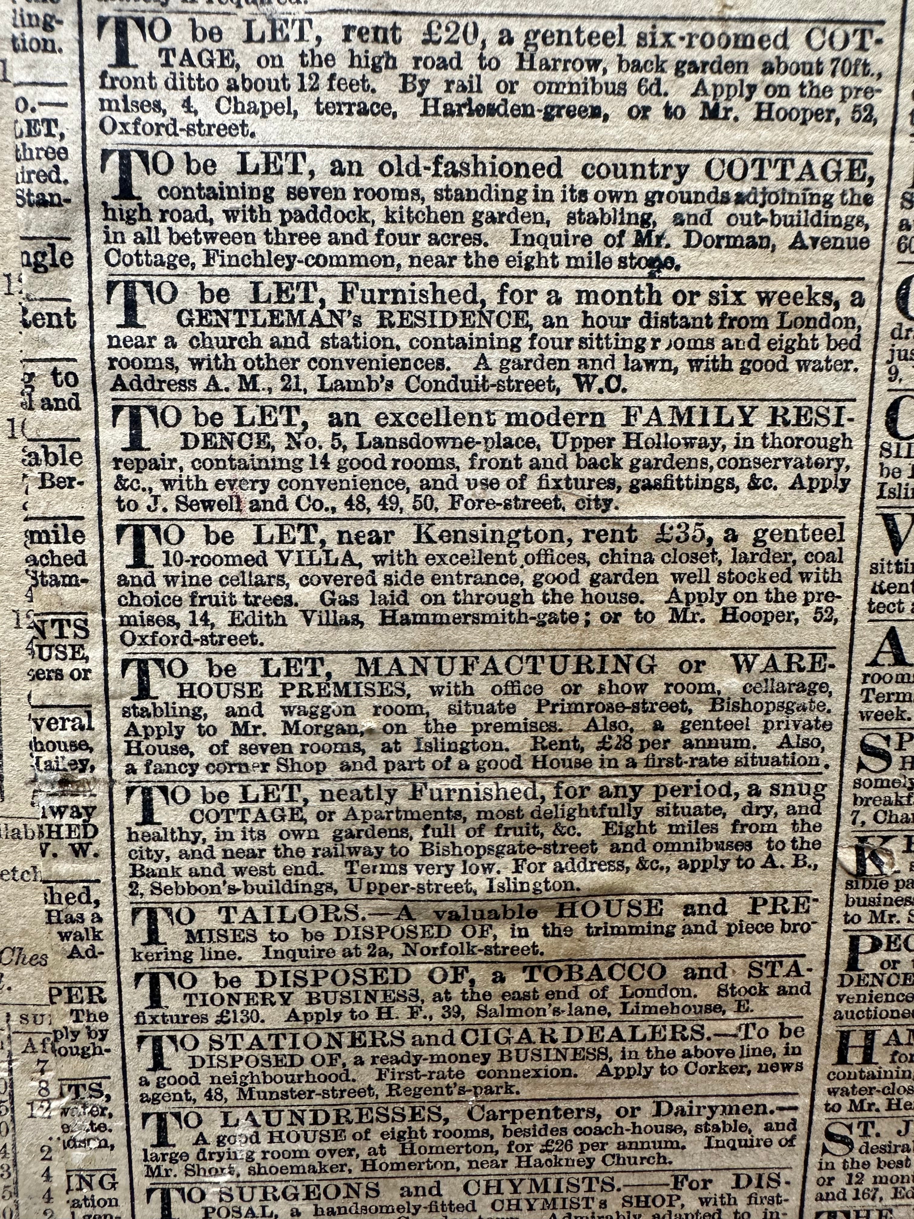 Vintage black and white newspaper page with to be let ads shown behind an antique painted pine trunk blanket box