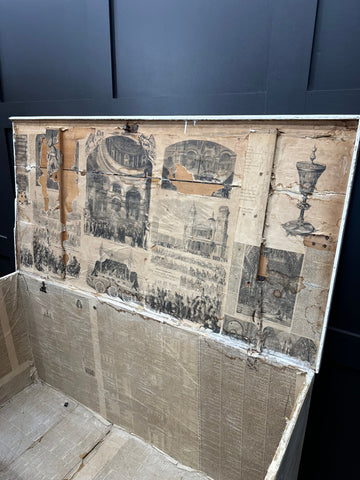 An aged pine trunk with a weathered exterior covered in faded black and white historical scenes perfect as a blanket box