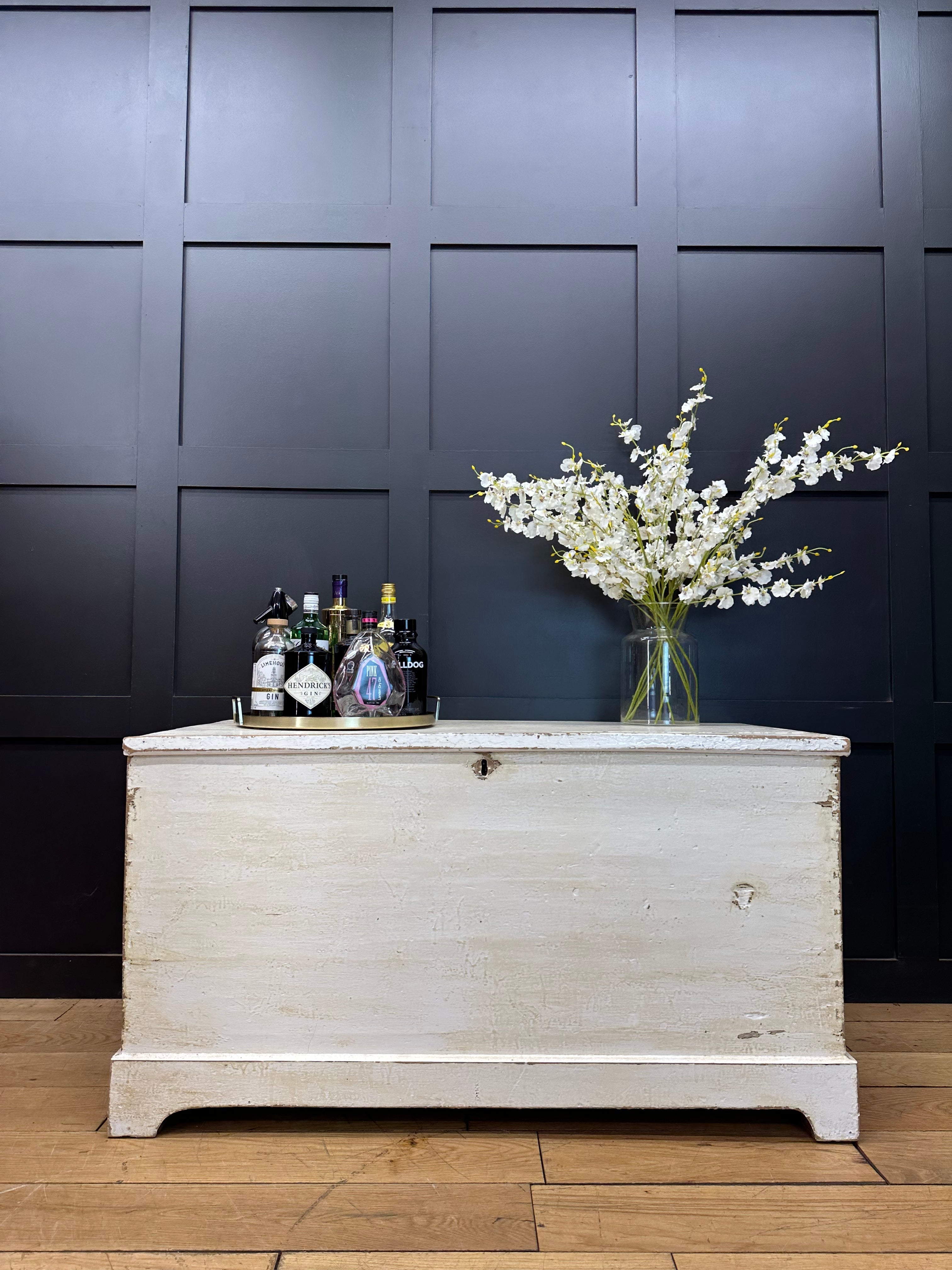 White distressed wooden pine trunk with metal corner hardware and small lock for storage or sideboard use