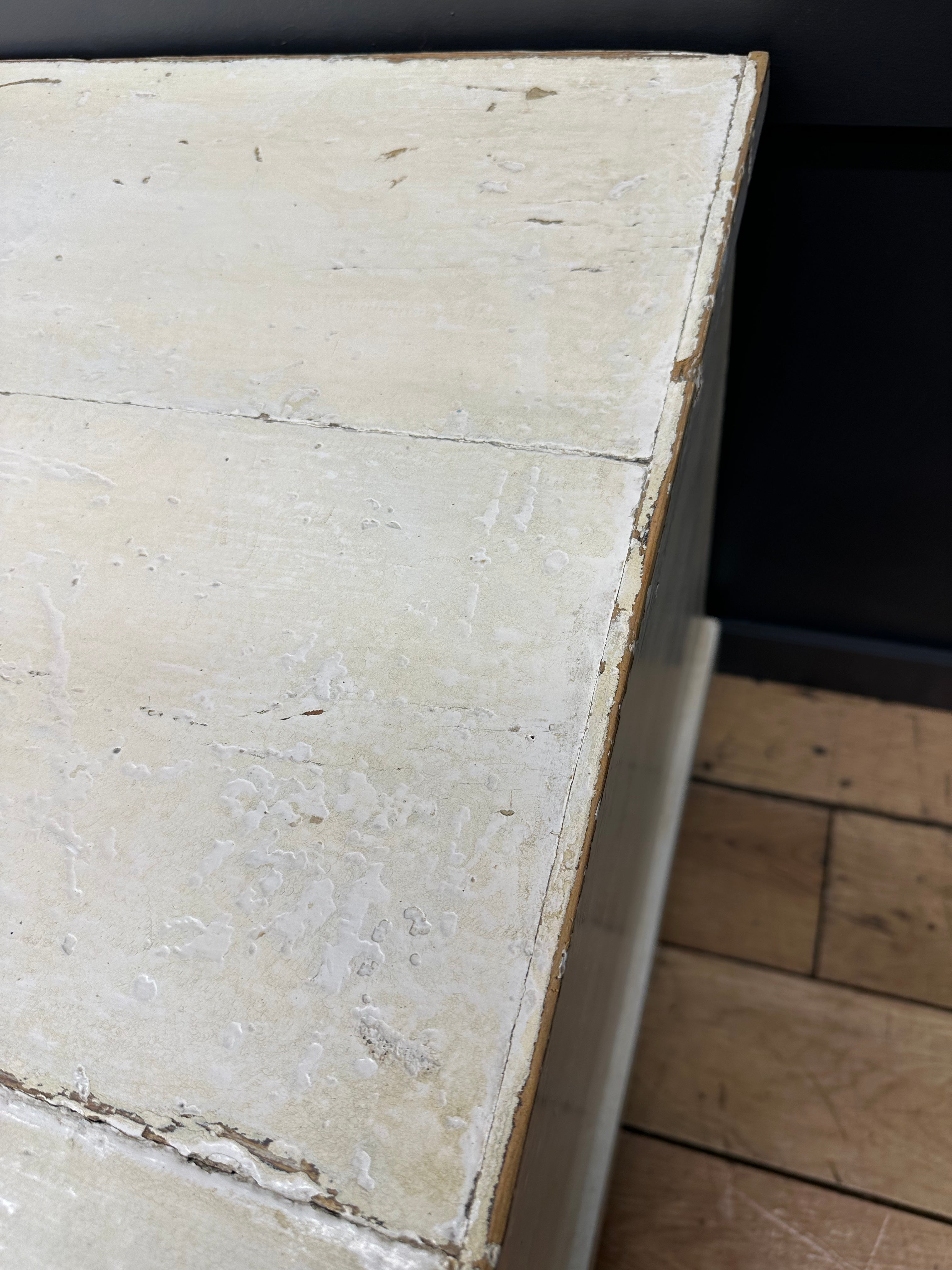 Distressed white painted antique pine trunk corner with chipped paint and visible wood grain on old pine chest