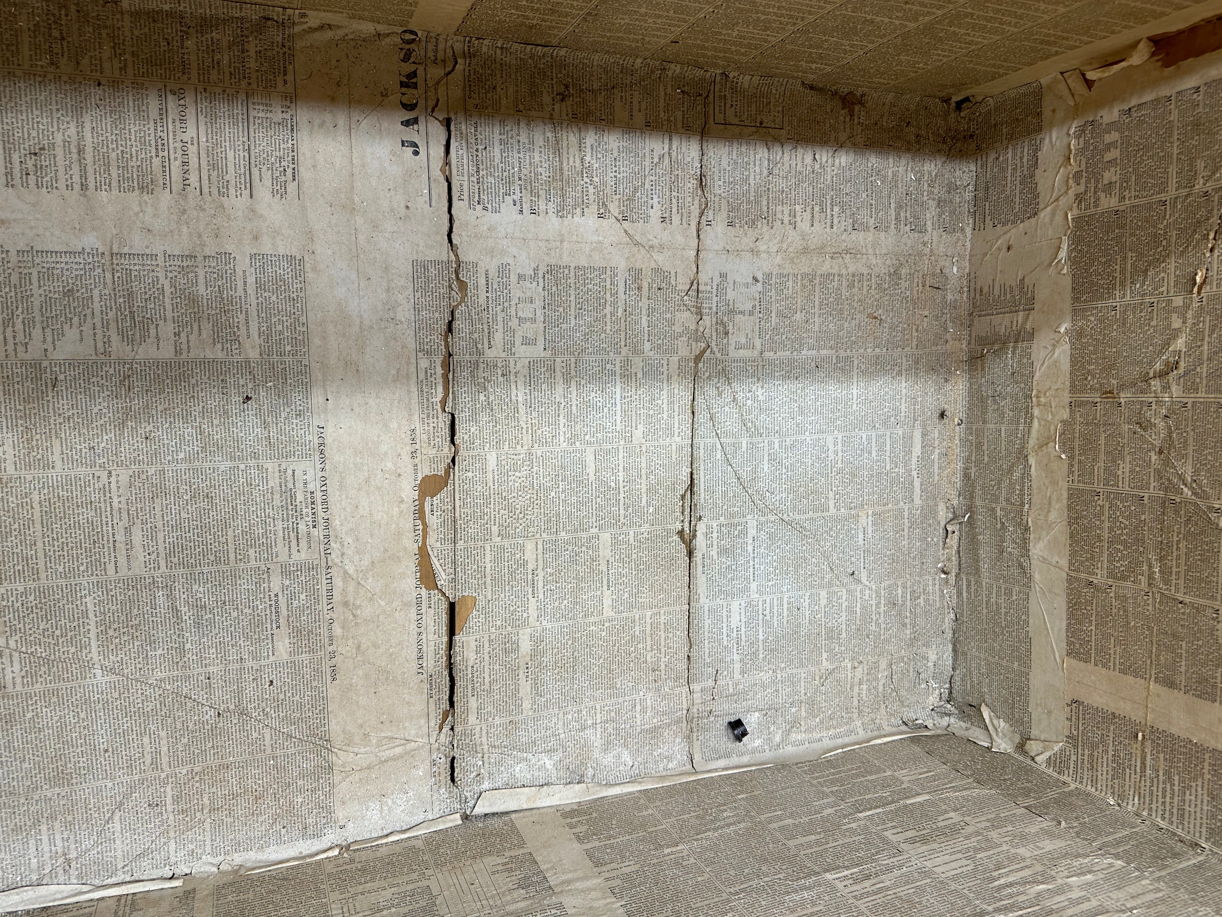 A weathered beige pine trunk covered in torn newspaper with visible creases perfect as an antique blanket box