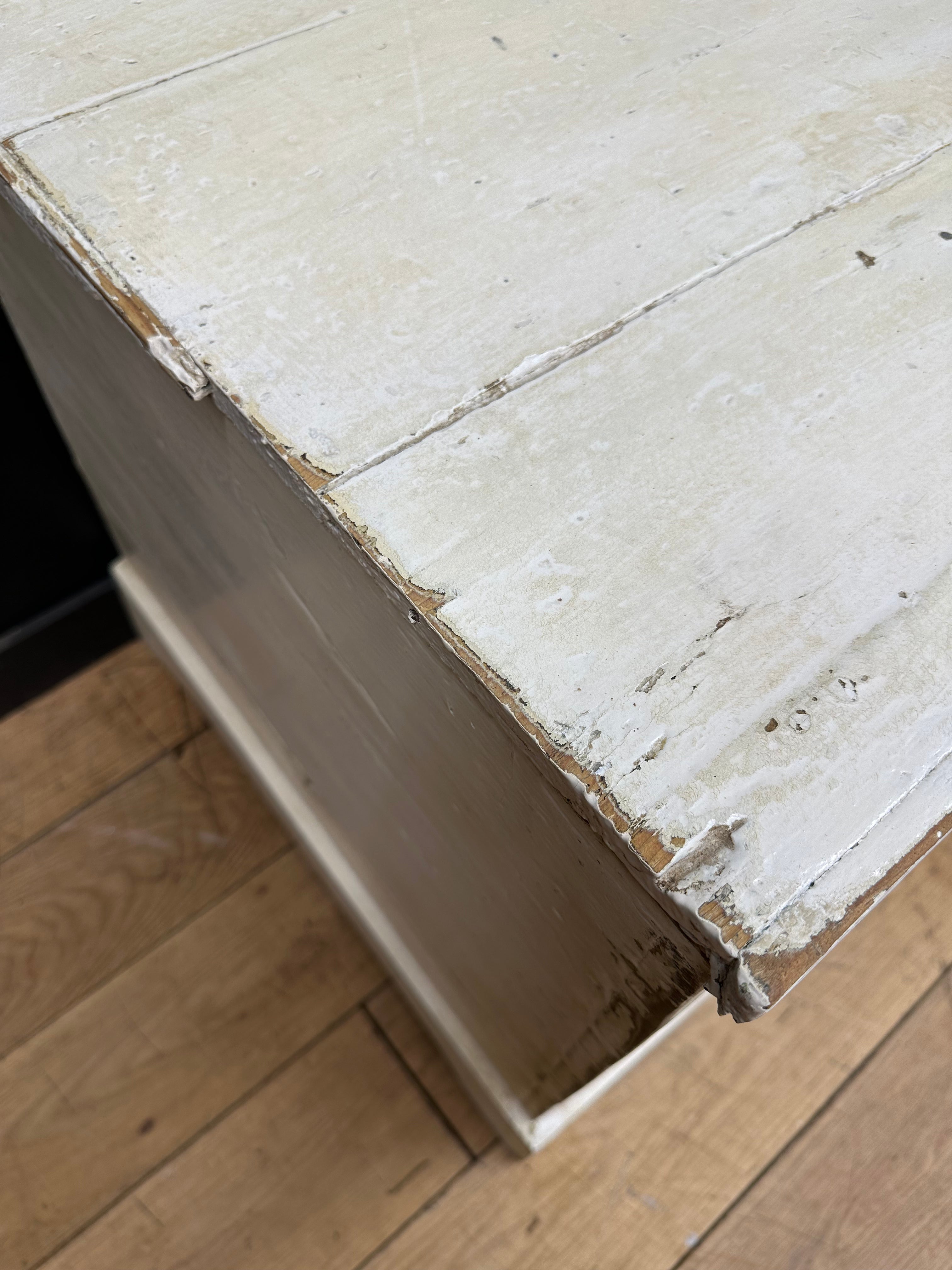 A weathered white painted pine trunk chest with chipped paint and visible wood grain perfect as a blanket box or sideboard