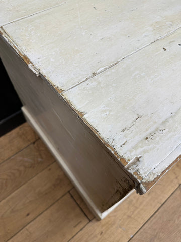A weathered white painted pine trunk chest with chipped paint and visible wood grain perfect as a blanket box or sideboard