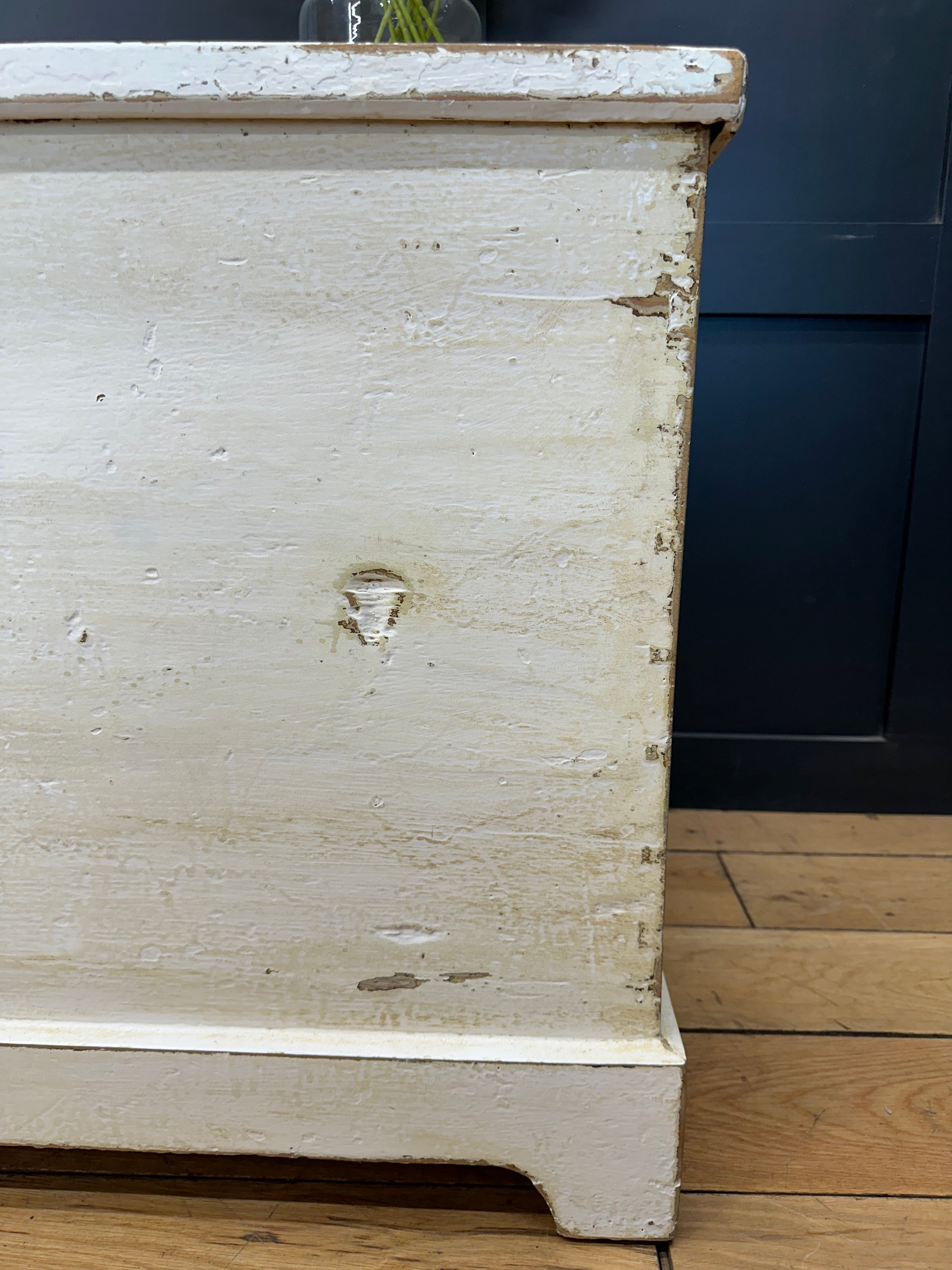 A distressed white painted pine trunk with chipped paint and a rustic vintage look perfect as a blanket box or sideboard
